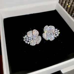 Detailed close-up of sparkling zircon flower stud earrings displayed in a white gift box