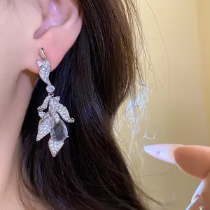 Close-up detail of elegant silver leaf earrings with sparkling water-drop zircon.