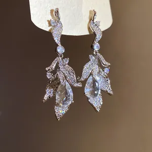 Detailed view of silver dangle earrings with leaf design and clear zircon drops.