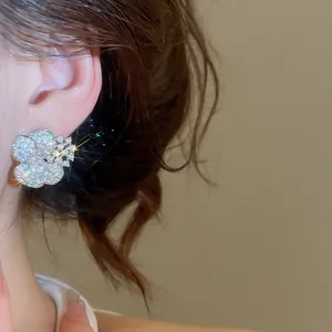 Close-up of sparkling zircon flower stud earring worn on a female ear detail view