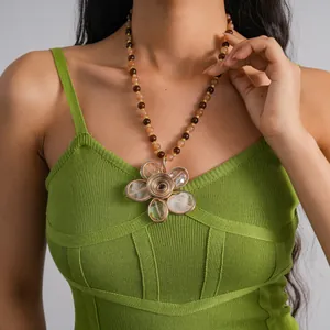 Primo piano di una collana con ciondolo a fiore vintage con perline color ambra.