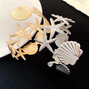 Detail view of gold and silver arm cuffs featuring starfish and seashell designs.