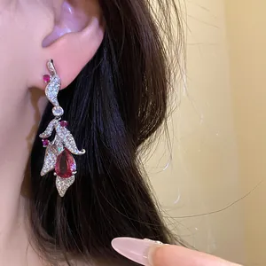 Close-up of elegant leaf dangle earring with teardrop red zircon on model's ear