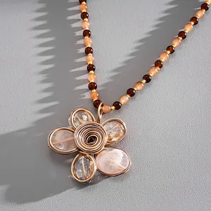 Dettaglio ravvicinato di una collana vintage con ciondolo a fiore e perline di cristallo