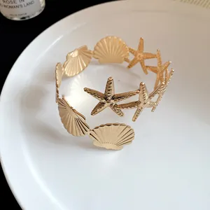Close-up detail of gold-tone metal starfish and shell patchwork armlet fashion bracelet