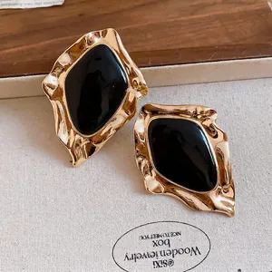 Vintage irregular gold-tone stud earrings with black enamel center and metal texture