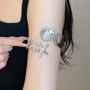 Macro view of silver metal arm cuff with starfish and shell design details.