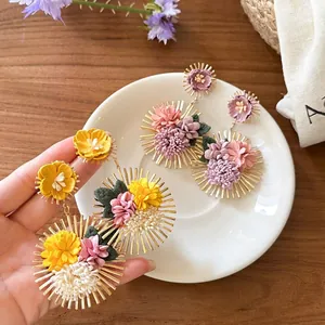 Close-up view of bohemian style floral drop earrings featuring gold sunburst metal texture