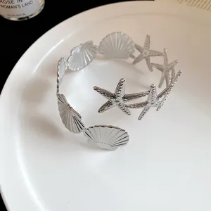 Detailed close-up view of a silver arm ring with starfish and seashell patterns