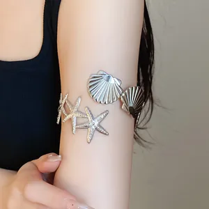 Macro detail of silver metal arm cuff bracelet featuring starfish and seashell design