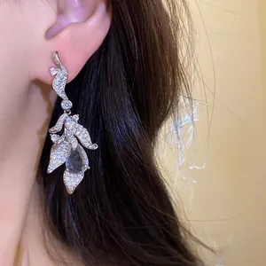 Detailed macro shot of elegant silver zircon leaf teardrop drop earrings on ear