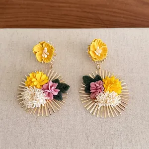Detailed view of bohemian ethnic flower earrings with yellow and pink fabric blossoms