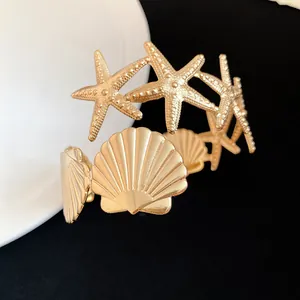 Detailed macro view showing the textured gold starfish and seashell design on this metal arm cuff