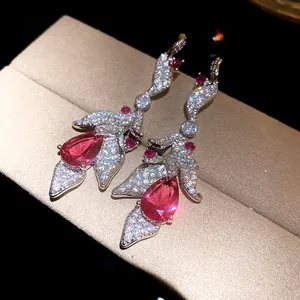 Close-up of sparkling zircon leaf drop earrings with pink water-drop gemstone