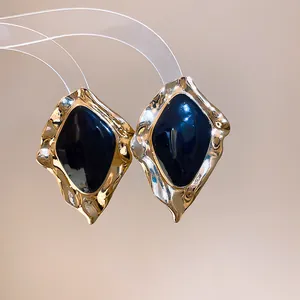 Close-up detail of vintage irregular gold-tone earrings with deep blue enamel inlay