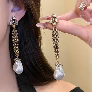 Détail de boucles d'oreilles feuilles de blé vintage avec perles baroques élégantes.