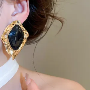 Vintage irregular gold-tone stud earrings with glossy black enamel center piece
