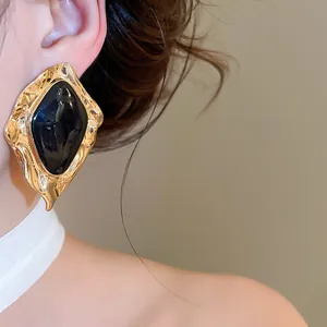 Close-up view of vintage irregular gold earrings featuring a black drip oil center