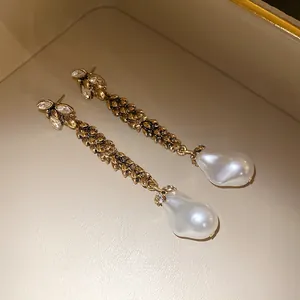 Détail rapproché de boucles d'oreilles épi de blé vintage avec perles baroques et strass