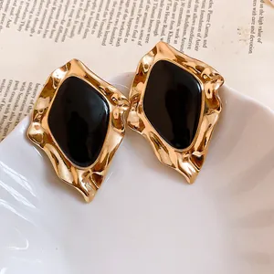 Detailed macro view of vintage irregular gold stud earrings with black enamel centers
