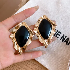 Close-up of vintage black drip oil irregular gold stud earrings in palace style.