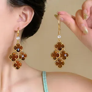 Close-up detail of vintage gold clover earrings with brown accents on a model's ear