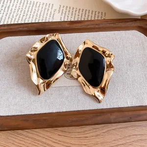 Macro detail view of vintage irregular gold earrings with black enamel center inlay