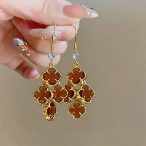 Close-up of vintage French style gold earrings with brown clover tassels and zircon.