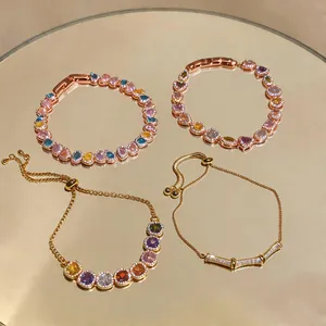 Detailed view of four colorful zircon bracelets with heart and round stones on a mirror surface