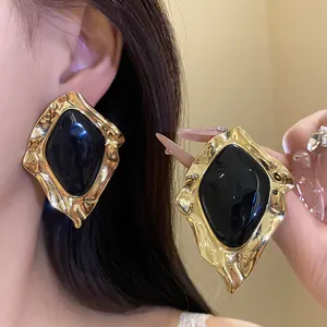 Close-up of vintage irregular geometric gold earrings with glossy black drip oil