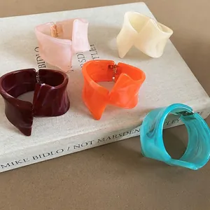 Elegante colección de cinco pulseras de resina de colores con formas geométricas retorcidas.
