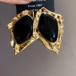 Detailed close-up showing the texture of vintage irregular gold earrings with black enamel inlay