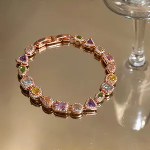 Close-up of rose gold bracelet featuring vibrant multi-color zircons in various shapes.