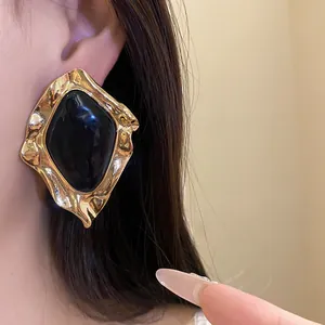 Detail view of vintage geometric irregular gold earrings with black enamel center