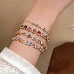 Close-up of layered dopamine colored zircon bracelets in gold and rose gold finishes.
