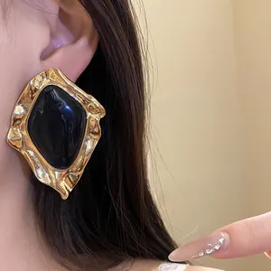 Detailed view of a vintage geometric earring with a black enamel center and gold frame.