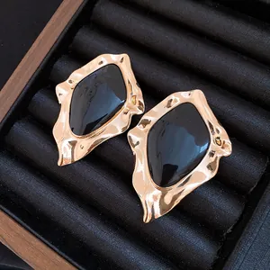Close-up of vintage irregular gold-tone earrings with black enamel inlay in a jewelry box