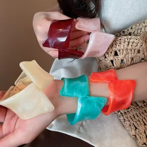 Primer plano de brazaletes de resina retorcidos de colores con textura de mármol.
