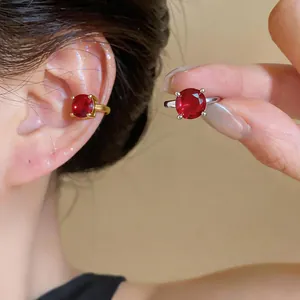 Primo piano di un ear cuff placcato oro 18k con zircone rosso su modella asiatica.
