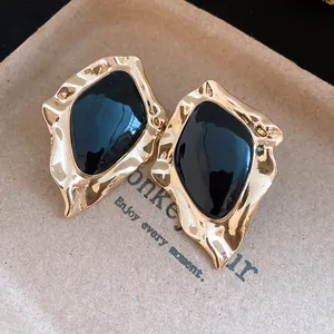 Detailed macro view of retro gold earrings featuring irregular shapes and black enamel centers