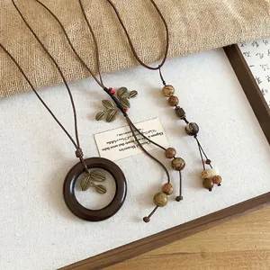 Vintage ethnic style necklace with leaf pendant and wooden beads on linen tray