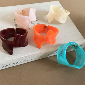 Brazaletes de resina geométricos irregulares con texturas arremolinadas en varios colores.