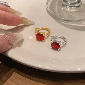 Dettaglio di clip per orecchi placcate oro e argento con brillanti zirconi rossi