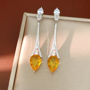 Primo piano di eleganti orecchini a goccia con brillanti zirconi gialli e bianchi.
