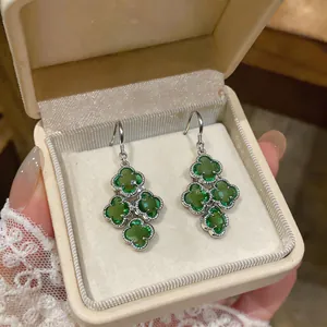 Detailed view of elegant green zircon flower dangle earrings presented in a beige jewelry gift box
