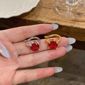 Dettaglio di orecchini a clip placcati oro 18k con zirconi rossi tondi argento e oro