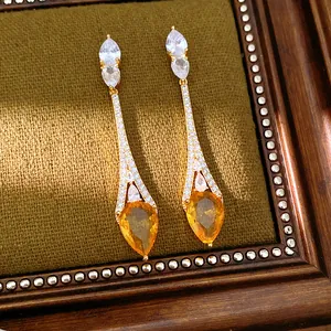 Dettaglio ravvicinato di orecchini placcati oro 18k con zirconi e goccia color ambra