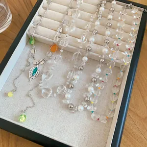 Close-up detail of French style pearl and clear beaded necklaces in a beige jewelry tray