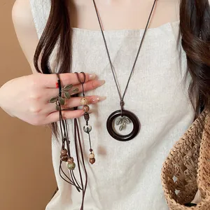 Detail of ethnic style long necklace with wooden ring and metal leaf pendant