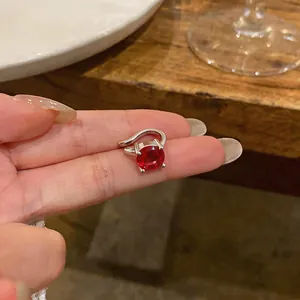 Vista macro dettagliata di un ear cuff argento con un grande zircone rosso di forma rotonda.
